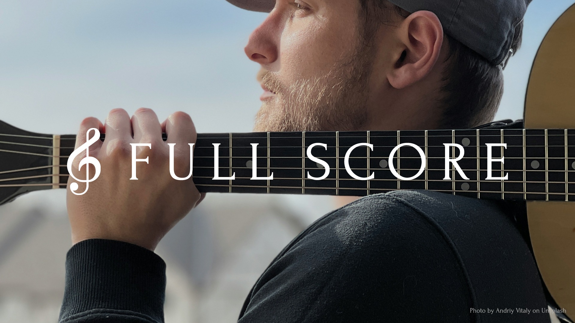 Photo of a man resting a guitar on his shoulder with the Full Score logo centered over the image.